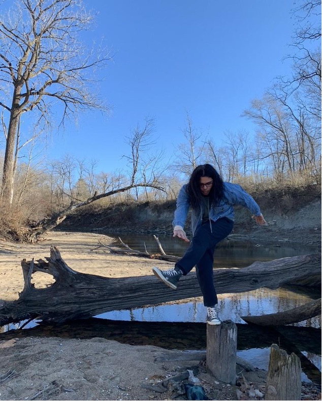 Austin posing on tree stumps at a riverbed. 