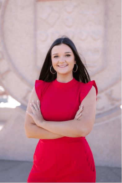 Elizabeth smiles at the camera. She has long brown hair and a red dress.