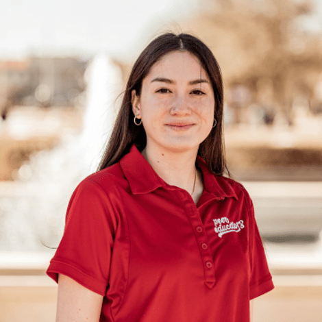 Erika smiles at the camera. She has straight brown hair and is wearing a red t-shirt.